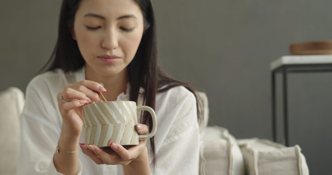 Woman Blowing Into The Cup of Coffee to Cool It