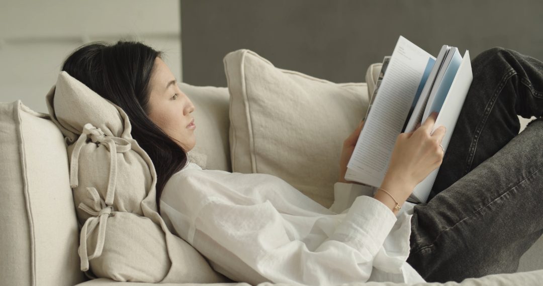 Woman Lying on The Couch Reading a Book