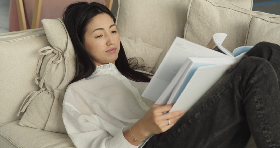 Woman Lying on Pillows Reading a Book