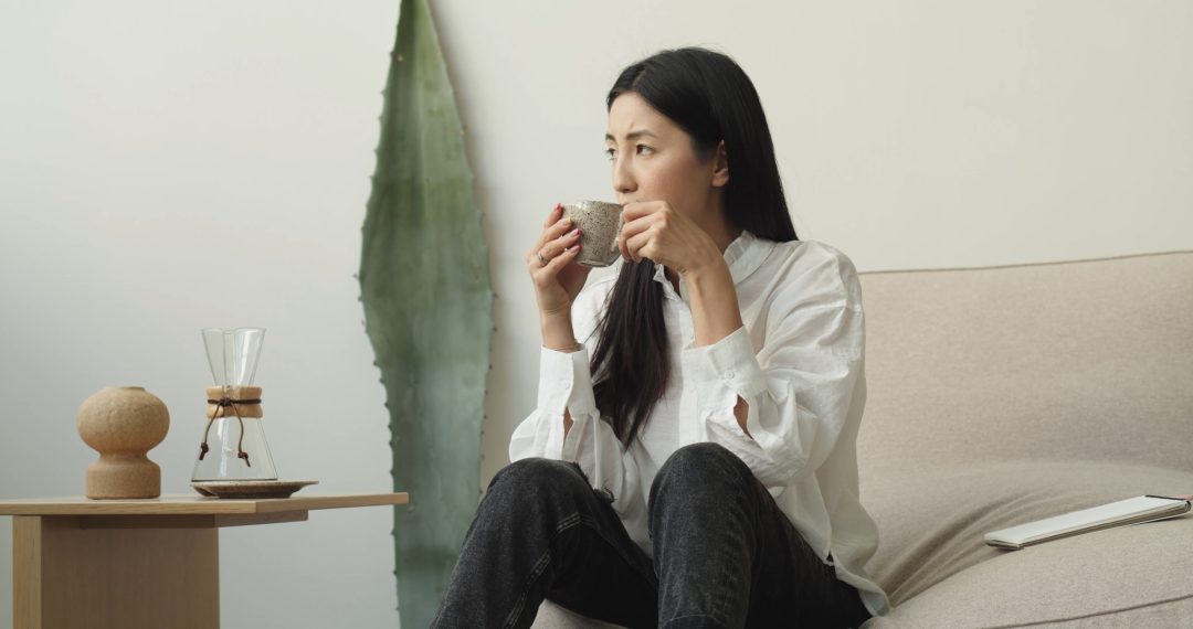 Woman Sitting on a Couch Drinking a Cup of Coffee