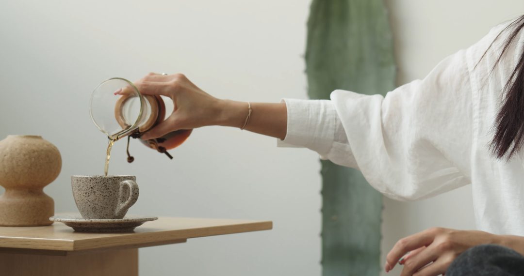 Woman at the Coffee Table Pouring Coffee into a Cup