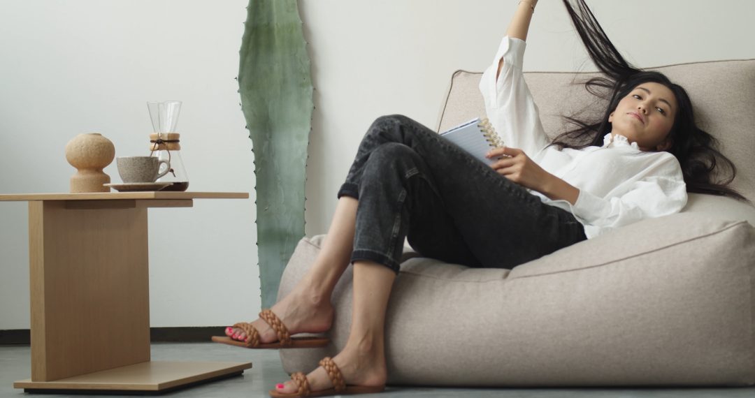 Woman Resting on a Couch and Playing with Hair