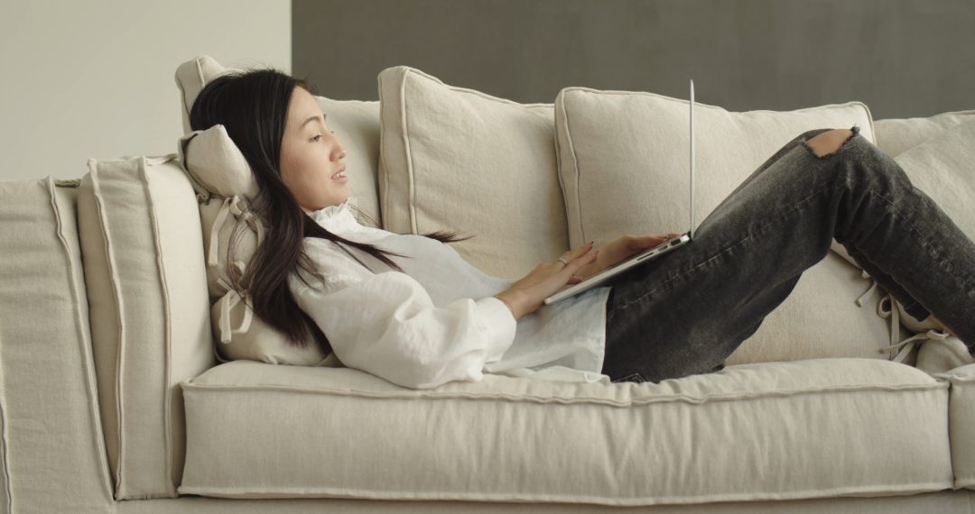 Woman Lying Down on the Couch with her Laptop, Remote Work on the Couch with an MacBook