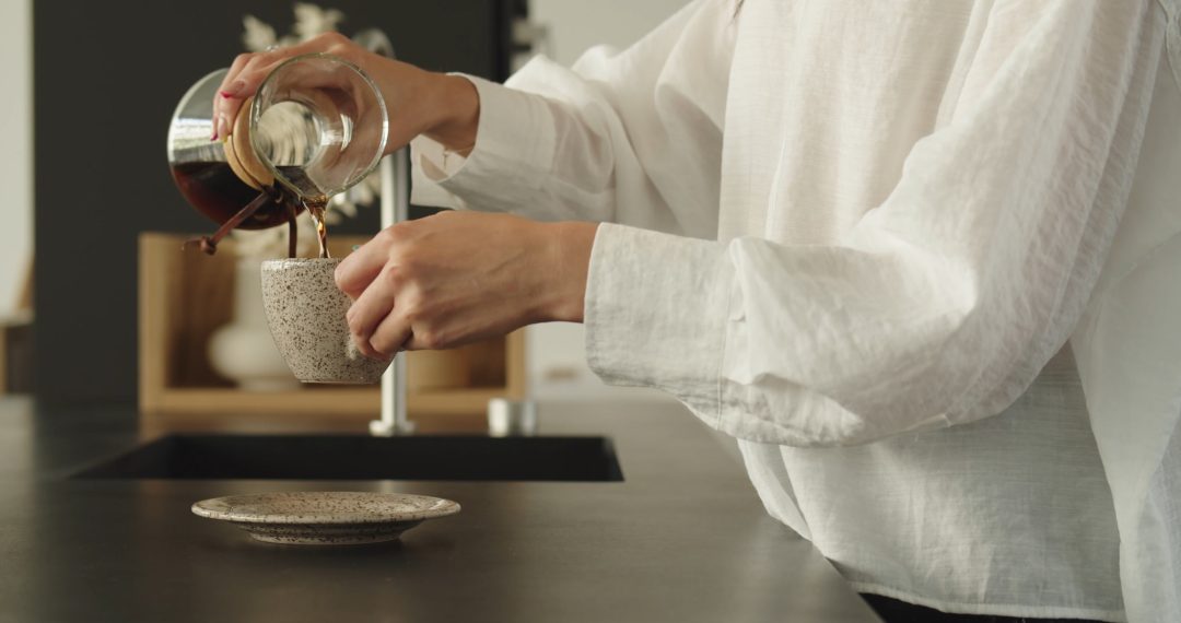 Woman Filling a Coffee Cup at the Kitchen Table