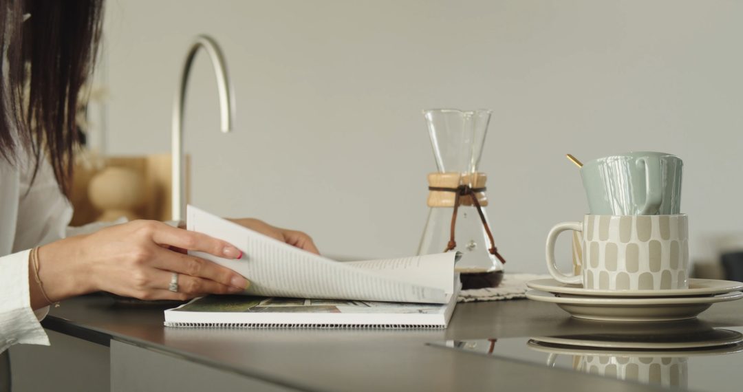 Woman Sitting at the Kitchen Table Reading a Book