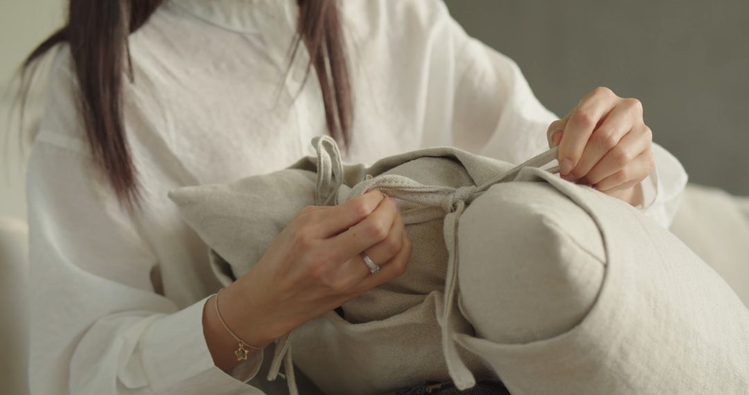 Close-up of A Woman with Painted Nails and Jewelry Tying a Knot on The Pillow