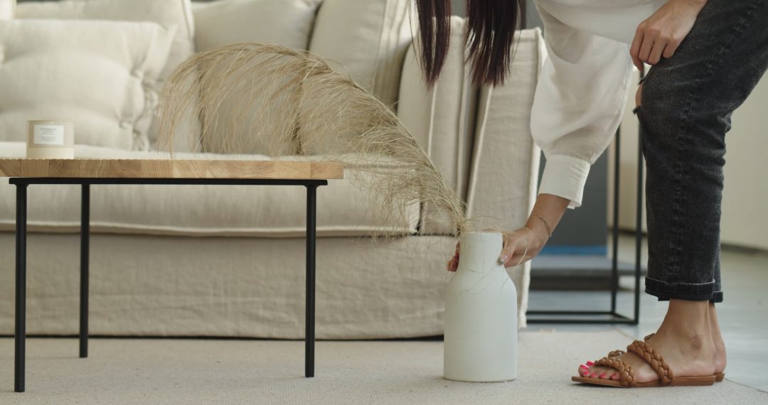 A Woman With Pink Pedicure Placing Decorative Vase next to the Table